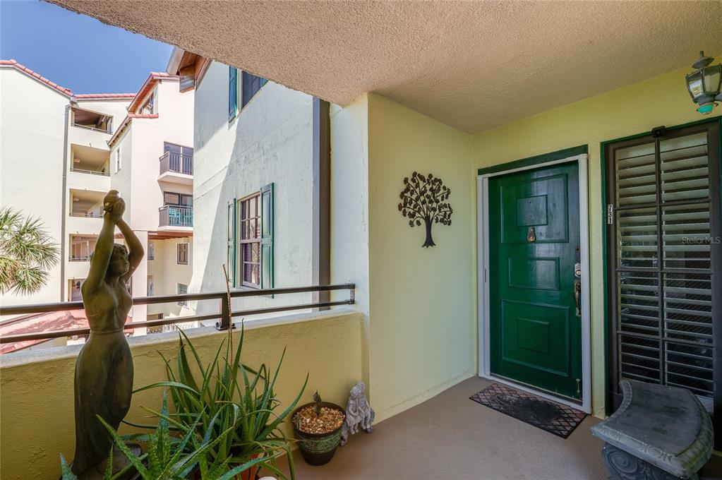 A balcony entrance features a green door, a statue, potted plants, and a metal tree decoration — 731 MARINA POINT DRIVE UNIT 731, DAYTONA BEACH, FL