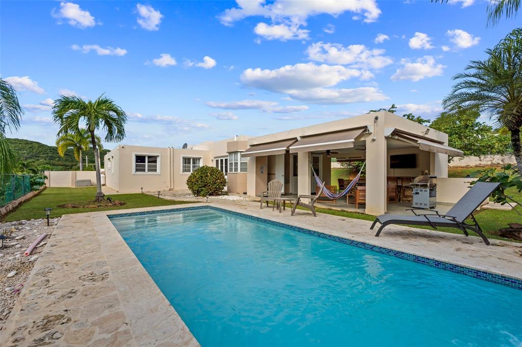A swimming pool sits in front of a house with a covered patio and lawn — 2A Calle del Sol CALLE DEL SOL, FAJARDO, PR