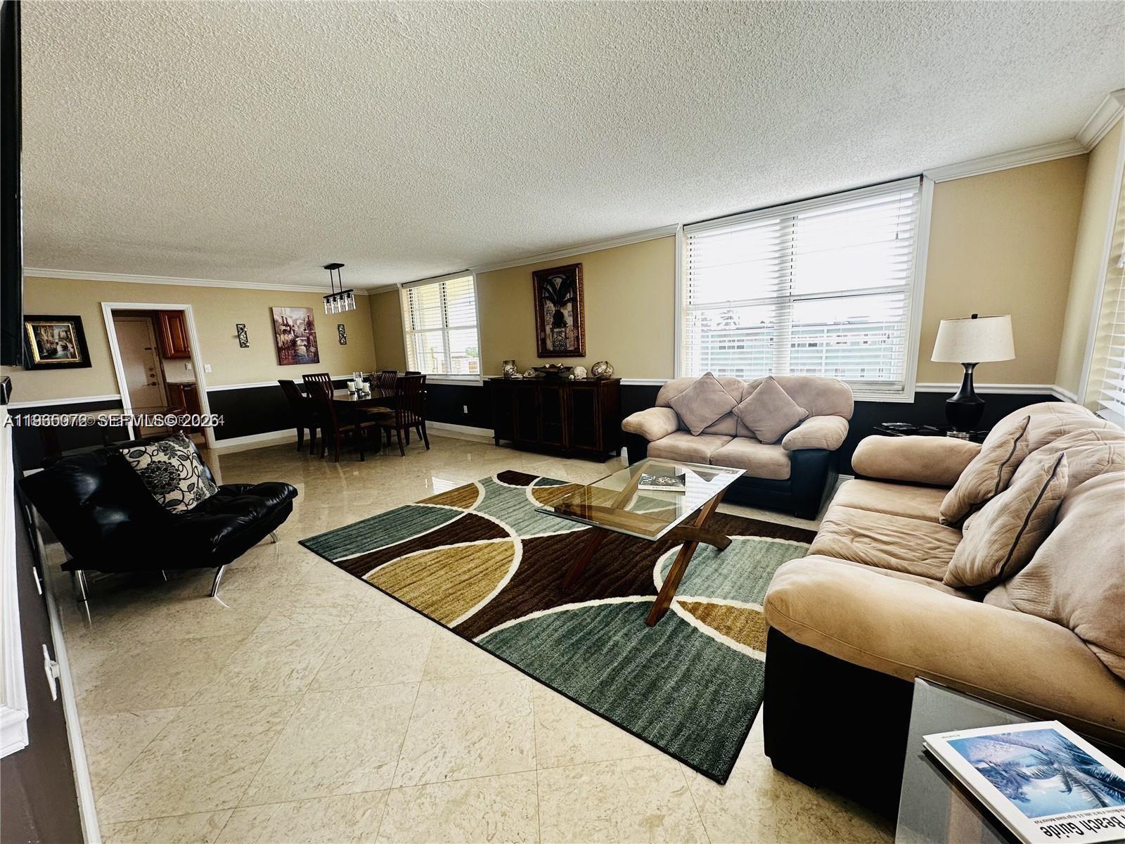 A spacious living and dining area features tile floors, neutral walls, and large windows — 1501 S Ocean Dr # 406, Hollywood FL 33019, HOLLYWOOD, FL