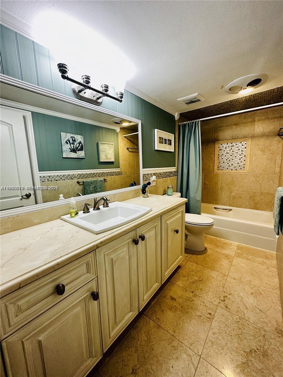 A bathroom features a vanity with a stone countertop, green walls, and a tiled tub — 1501 S Ocean Dr # 406, Hollywood FL 33019, HOLLYWOOD, FL