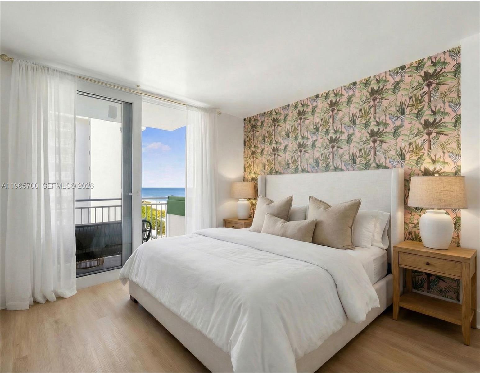 A bedroom features a palm-print accent wall, a white upholstered bed, and a balcony view — 345 Ocean Dr # 718, Miami Beach FL 33139, MIAMI BEACH, FL