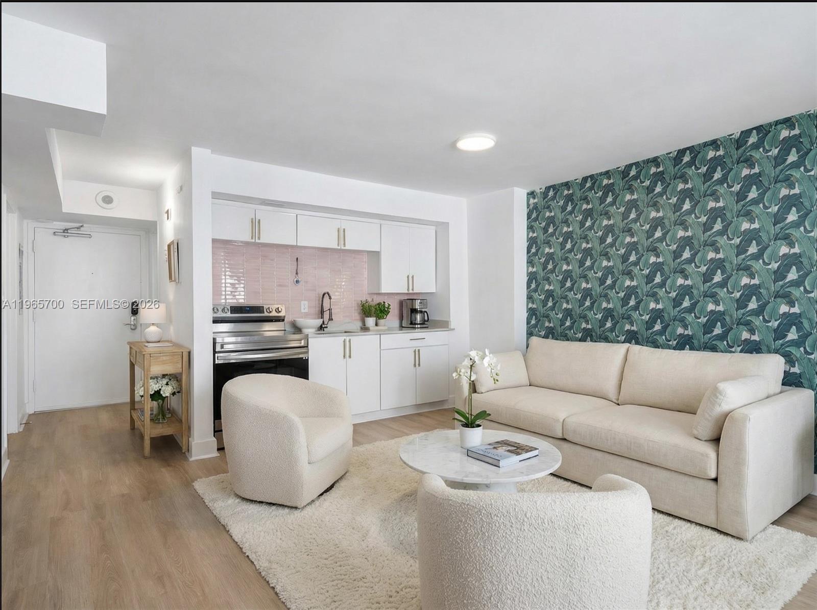 A studio apartment features a kitchen with pink tile, a sofa, and tropical leaf wallpaper — 345 Ocean Dr # 718, Miami Beach FL 33139, MIAMI BEACH, FL