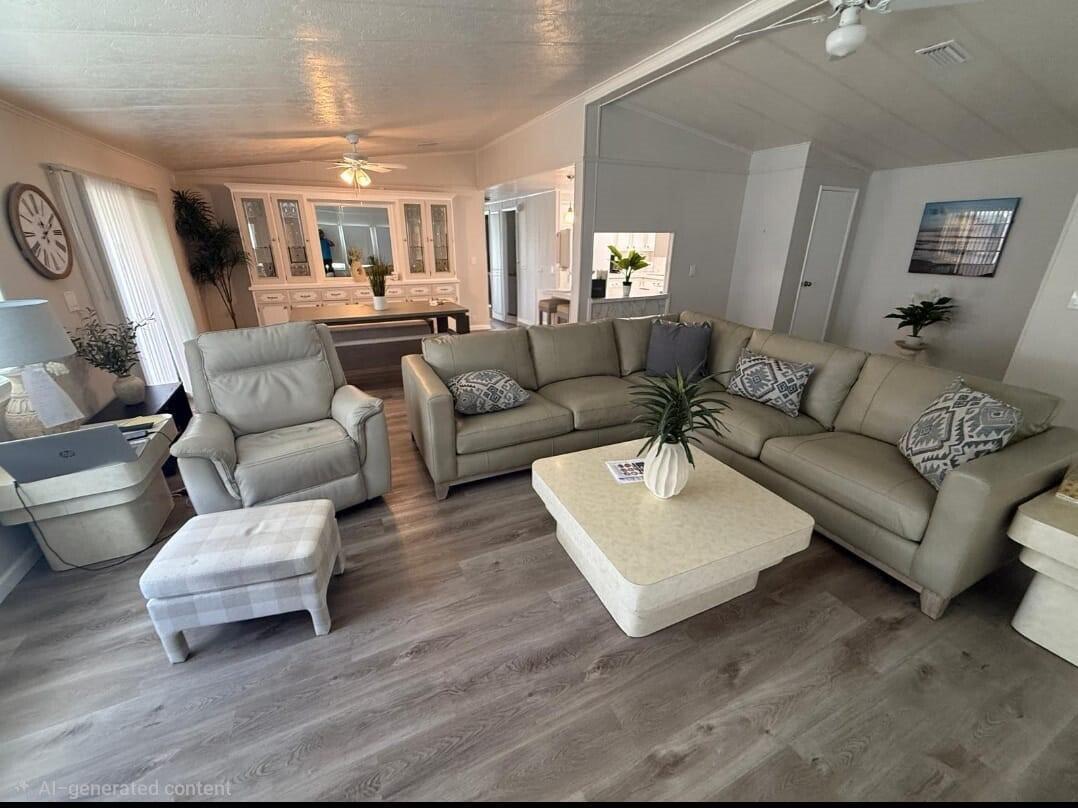 A living room with light wood flooring, a sectional sofa, an armchair, and a dining area — 698 Sunny South Avenue, Boynton Beach FL 33436, BOYNTON BEACH, FL