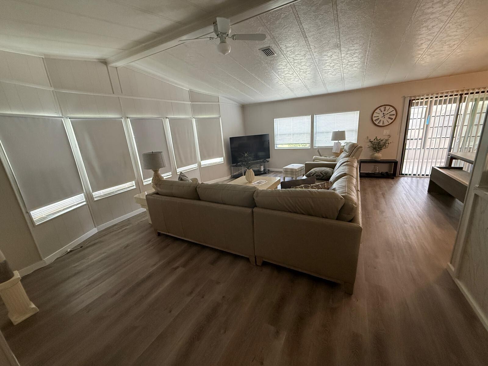 A living room features a large sectional sofa, light wood flooring, and multiple windows — 698 Sunny South Avenue, Boynton Beach FL 33436, BOYNTON BEACH, FL