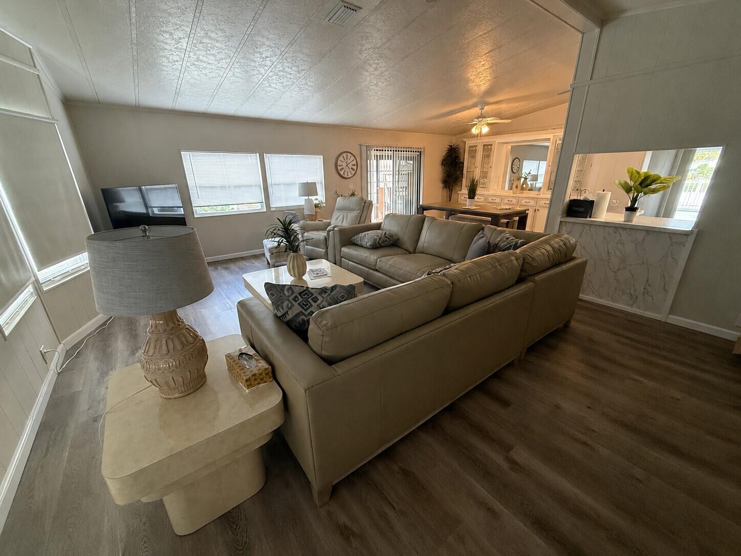 A living room features a large beige sectional sofa, a coffee table, and wood-look flooring — 698 Sunny South Avenue, Boynton Beach FL 33436, BOYNTON BEACH, FL