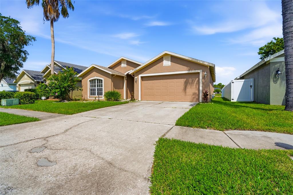 A tan single-story house with a two-car garage and a concrete driveway — 29417 CROSSLAND DRIVE, WESLEY CHAPEL, FL