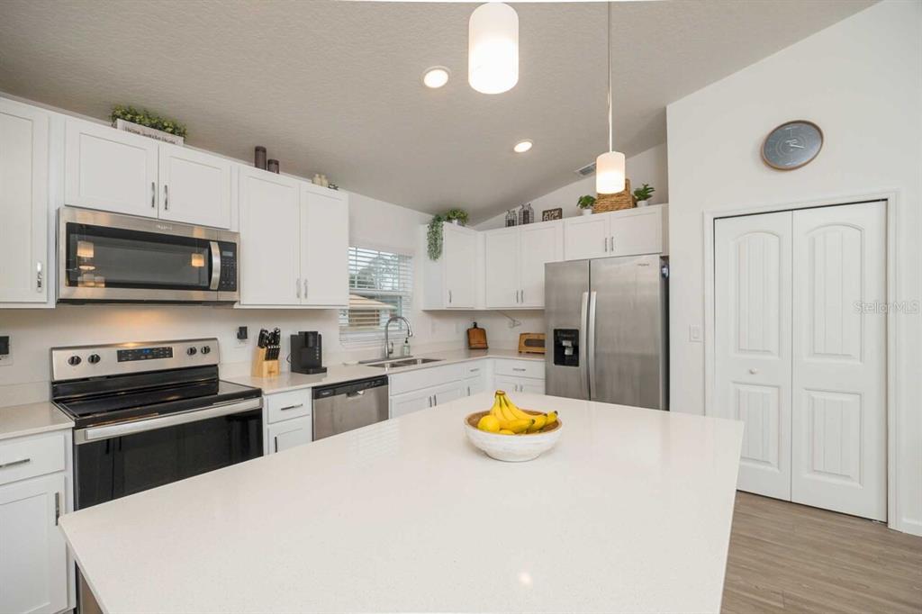 A kitchen features white cabinets, stainless steel appliances, a large island, and quartz countertops — 42 WOODBORN LANE, PALM COAST, FL