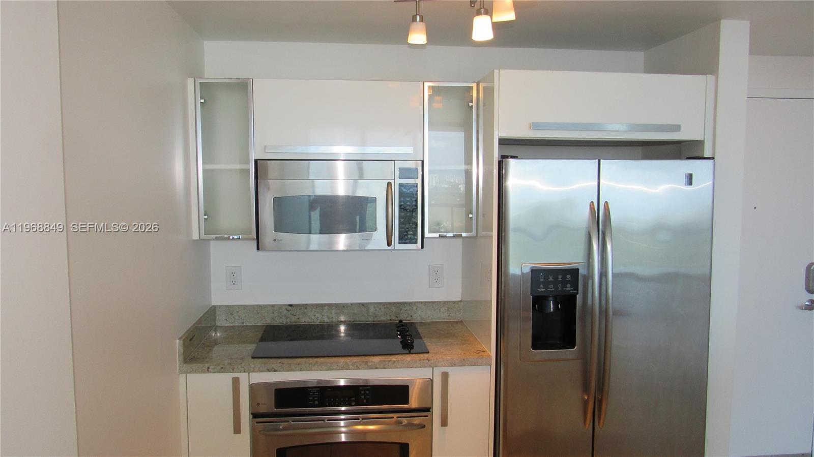 A kitchen features white cabinets, stainless steel appliances, and granite countertops — 601 NE 36th St # 2308, Miami FL 33137, MIAMI, FL