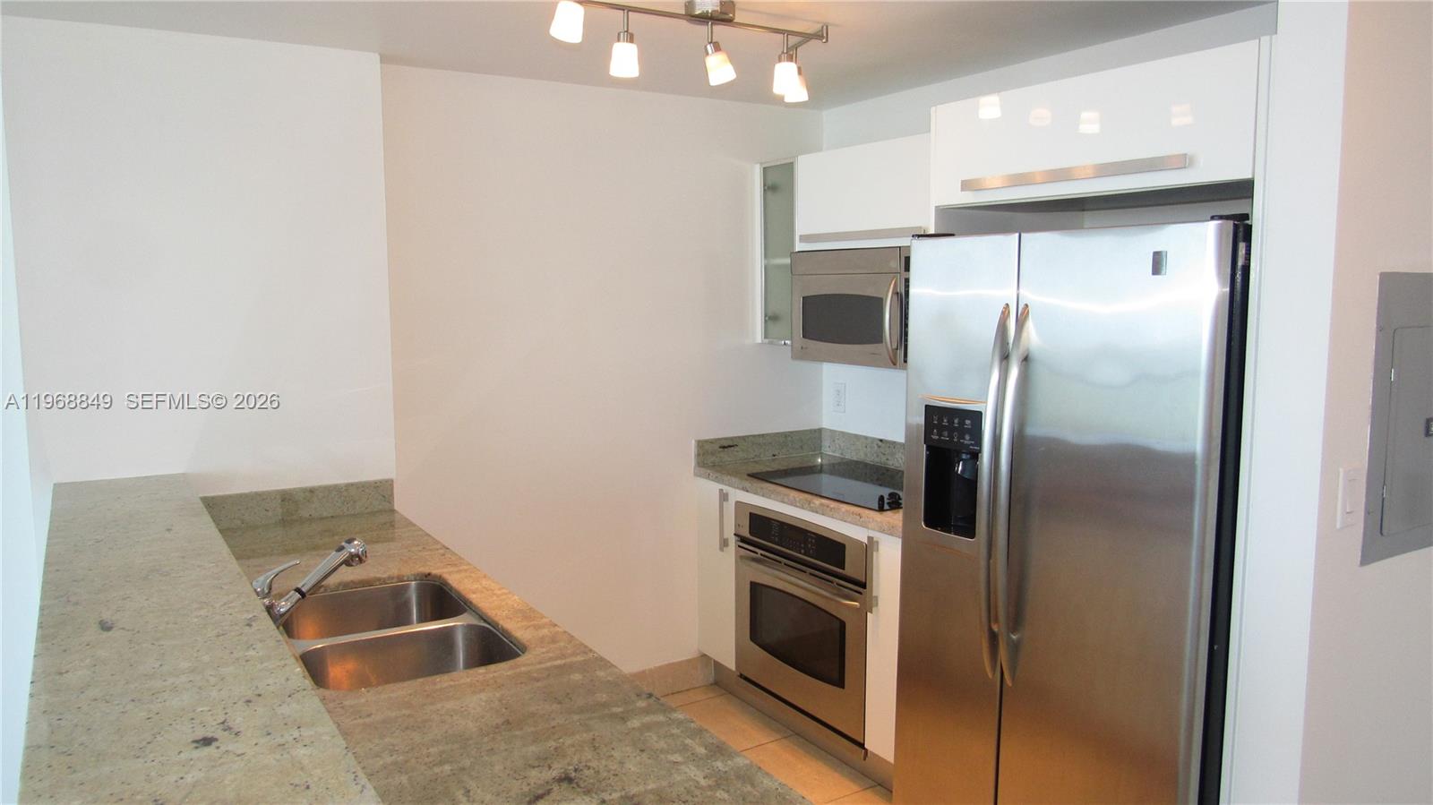 A kitchen features stainless steel appliances, white cabinets, and granite countertops with a double sink — 601 NE 36th St # 2308, Miami FL 33137, MIAMI, FL