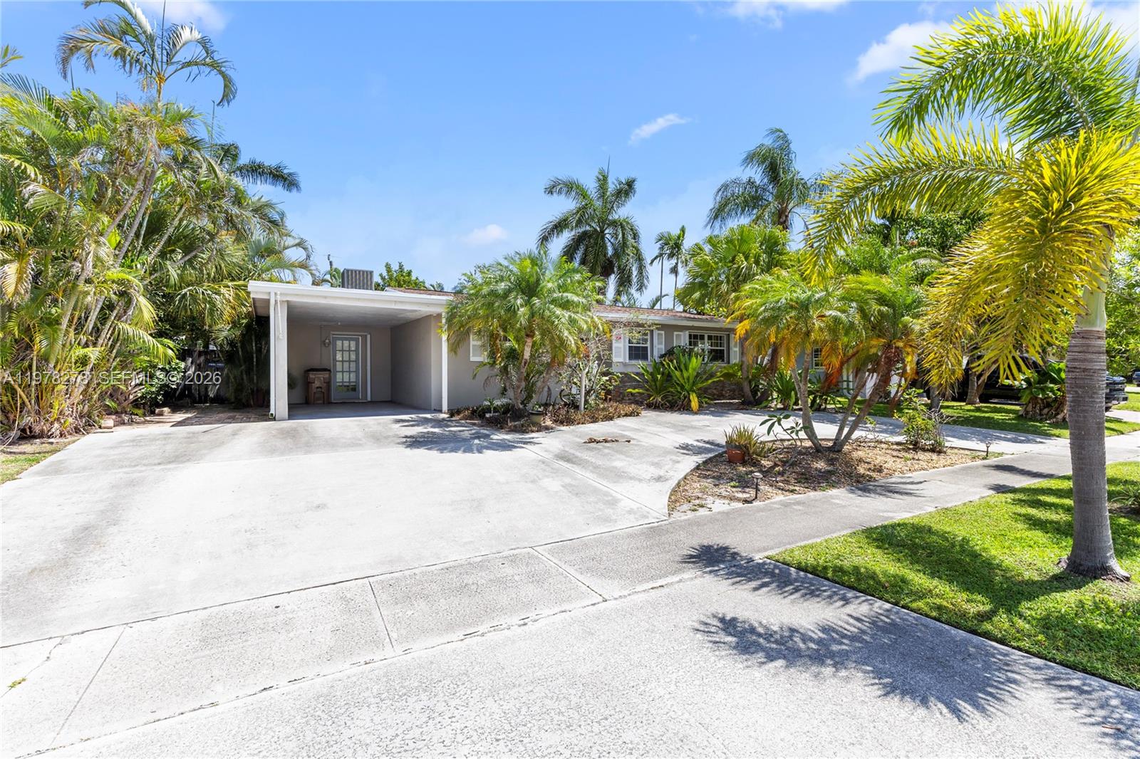 A single-story house with a carport and palm trees sits behind a concrete driveway — 809 SE 14th Dr, Deerfield Beach FL 33441, DEERFIELD BEACH, FL