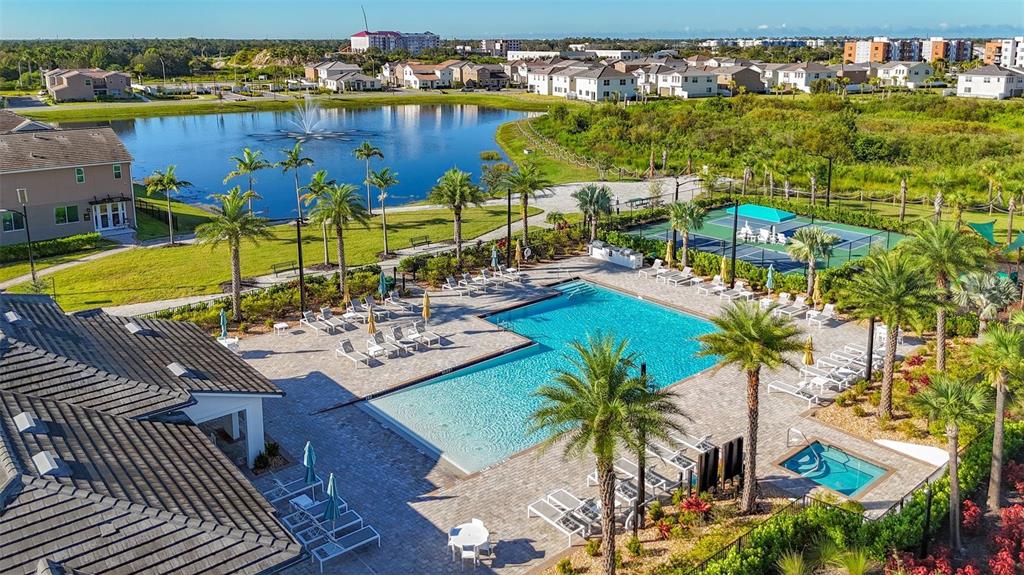 An aerial view shows a community swimming pool, hot tub, and tennis court near a lake — 5414 LATCHES LANE UNIT 3B-Haven, LAKEWOOD RANCH, FL