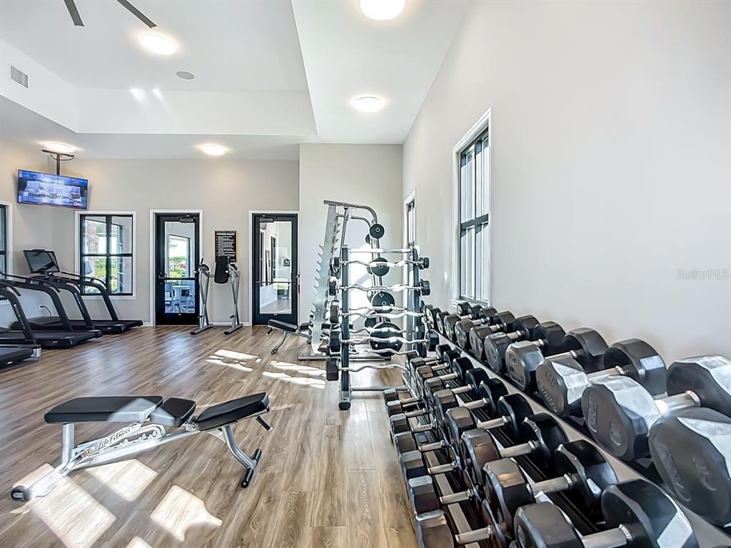 A gym features rows of dumbbells, a weight rack, treadmills, and a workout bench — 5414 LATCHES LANE UNIT 3B-Haven, LAKEWOOD RANCH, FL