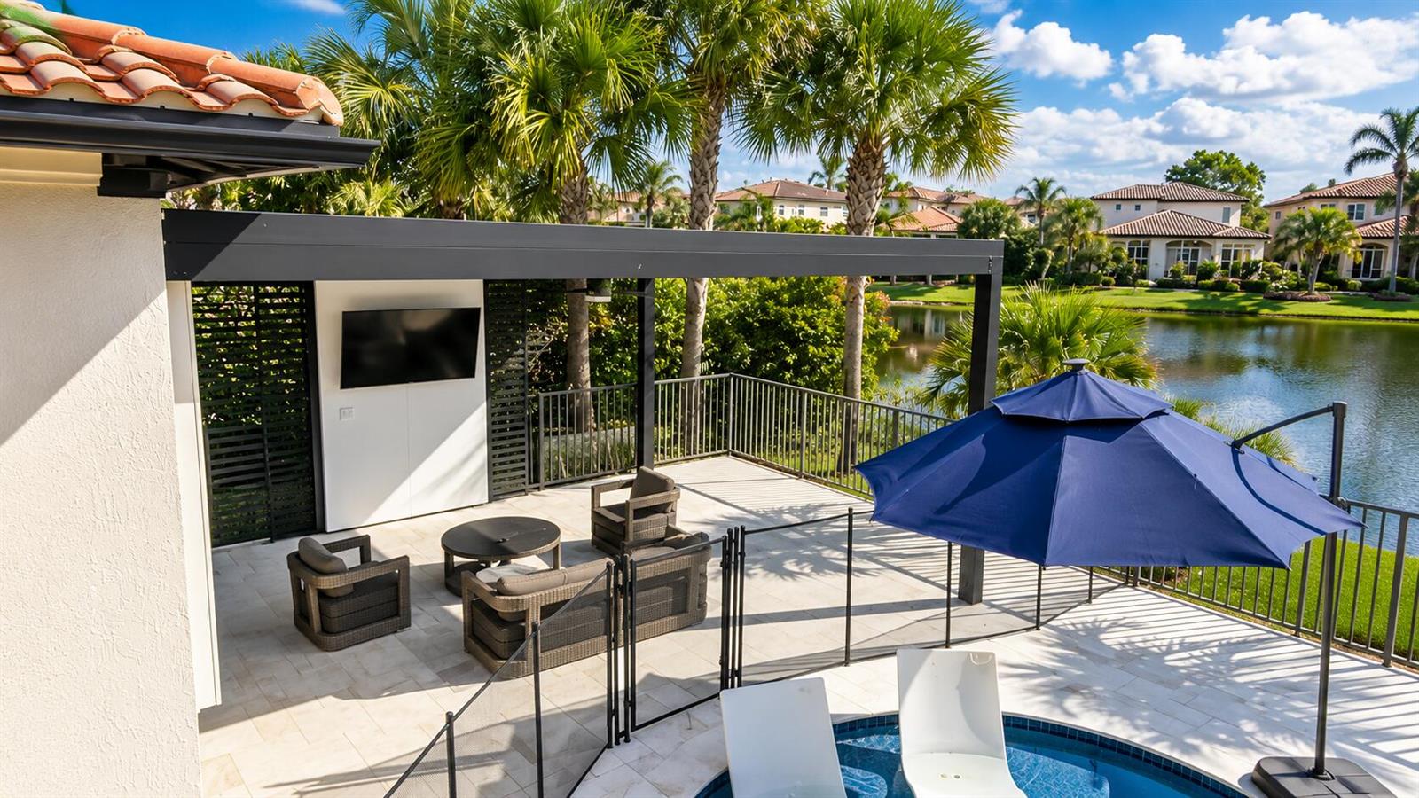 A living room features a blue chevron-patterned fireplace wall, a large sectional, and lake views — 8170 NW 124th Terrace, Parkland FL 33076, PARKLAND, FL
