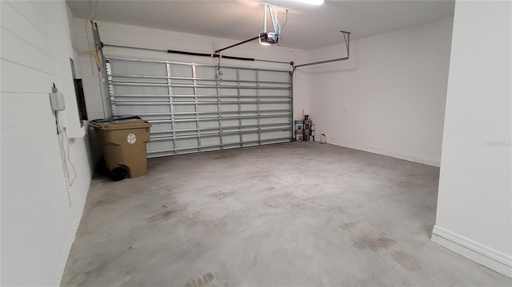 An empty garage with a concrete floor, white walls, and a metal roll-up door — 2127 BRILLANTE DRIVE, ST CLOUD, FL