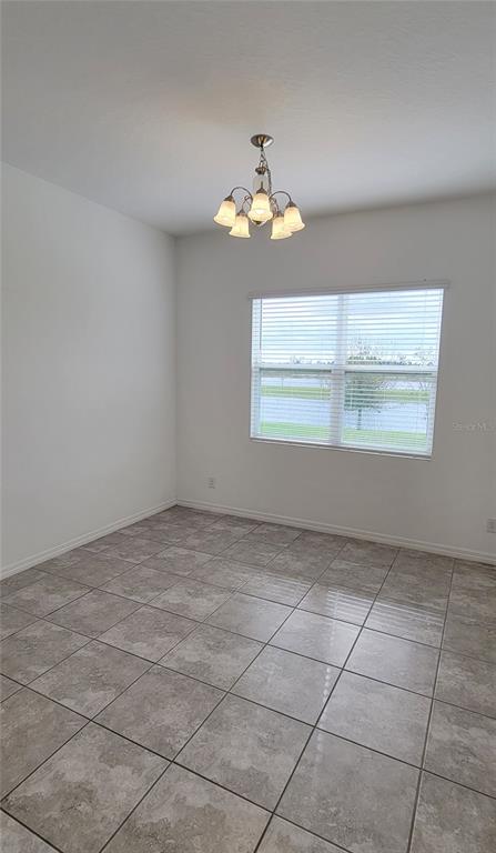 A dining room with white walls, tile flooring, a chandelier, and a window with blinds — 2127 BRILLANTE DRIVE, ST CLOUD, FL