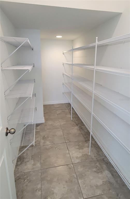 A walk-in pantry features white wire shelving on both sides and gray tile flooring — 2127 BRILLANTE DRIVE, ST CLOUD, FL