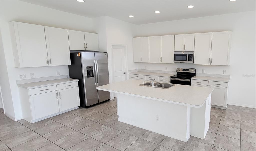 A kitchen with white cabinets, stainless steel appliances, a center island, and tiled flooring — 2127 BRILLANTE DRIVE, ST CLOUD, FL