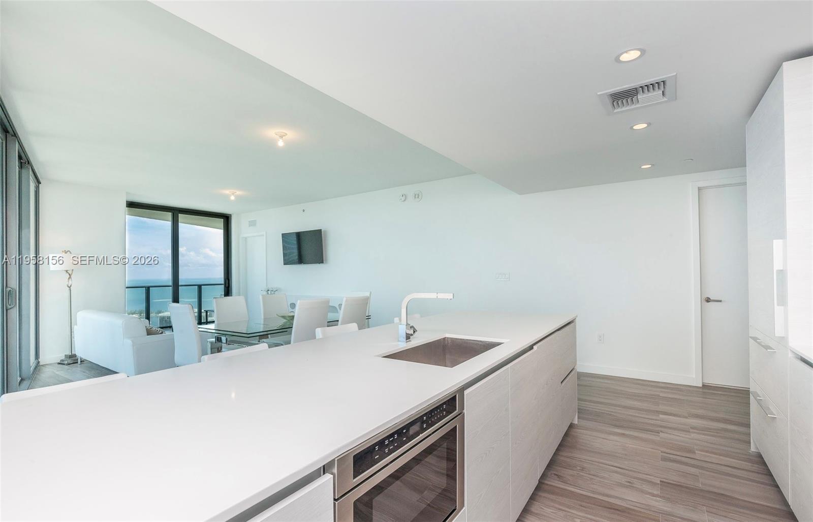 A modern kitchen island with a stainless steel oven overlooks a dining area and ocean — 1300 S Miami Ave # 4505, Miami FL 33130, MIAMI, FL