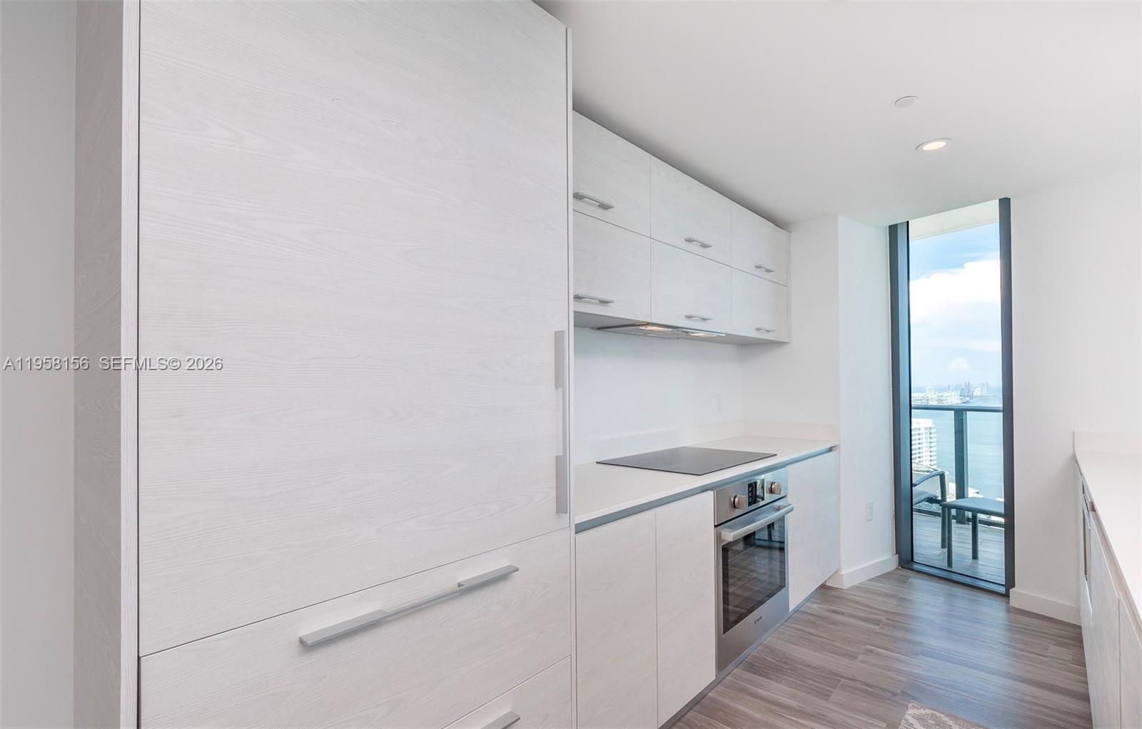 A modern kitchen features light wood-grain cabinetry, stainless steel appliances, and a balcony with water views — 1300 S Miami Ave # 4505, Miami FL 33130, MIAMI, FL