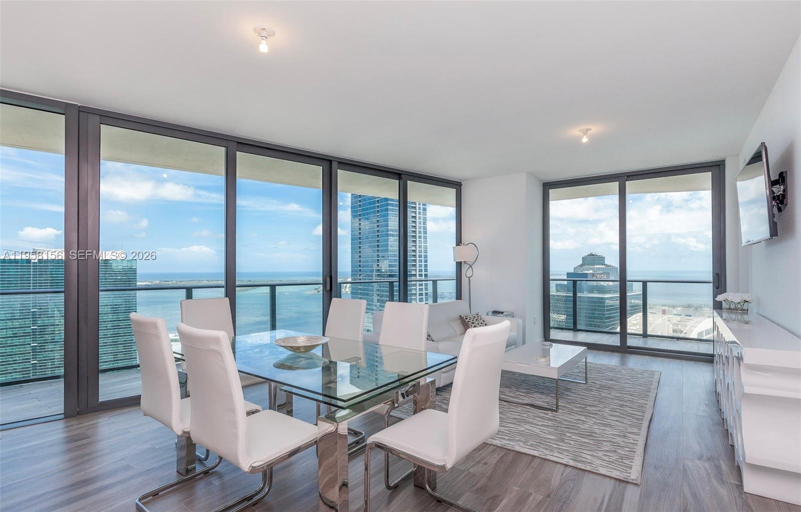 A modern dining and living area features floor-to-ceiling windows with expansive ocean and city views — 1300 S Miami Ave # 4505, Miami FL 33130, MIAMI, FL