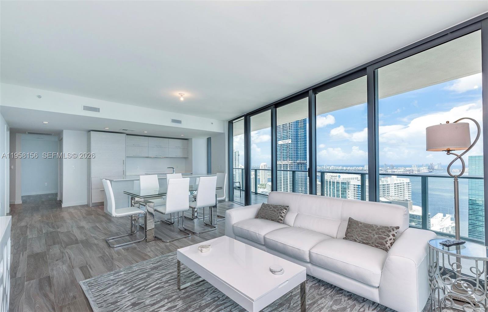 A modern living and dining area features white furniture, wood-look flooring, and floor-to-ceiling windows — 1300 S Miami Ave # 4505, Miami FL 33130, MIAMI, FL