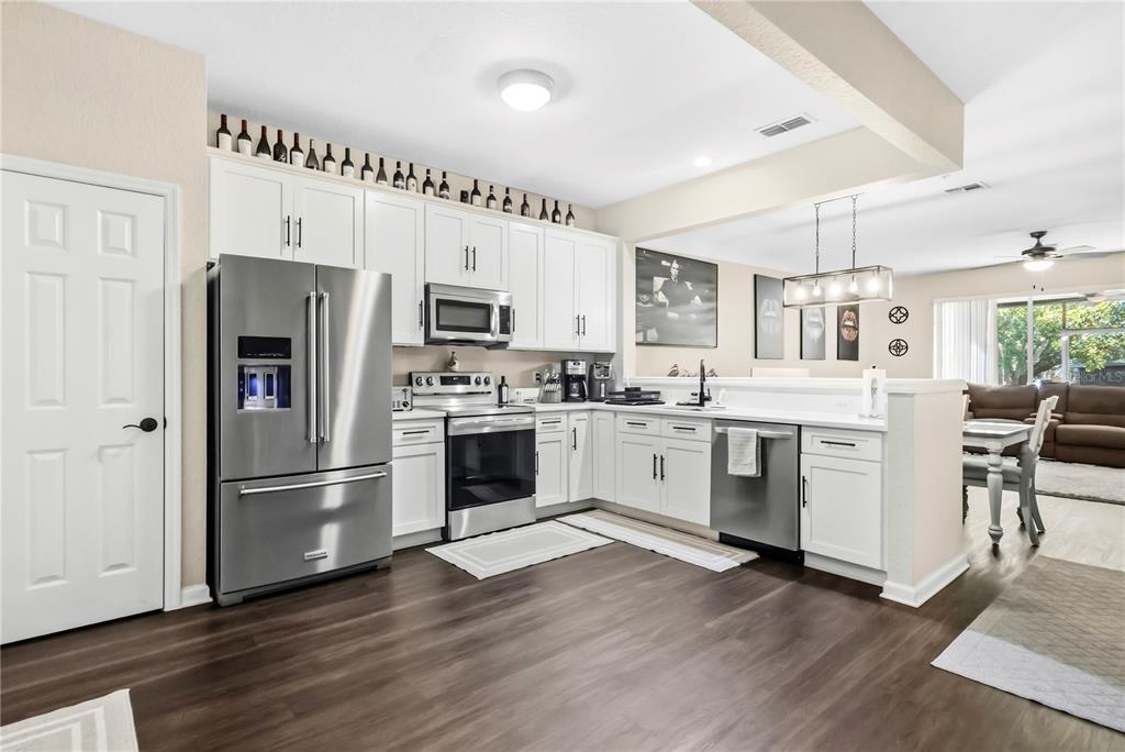 A kitchen with white cabinets, stainless steel appliances, and dark wood-look flooring — 6480 RANELAGH DRIVE UNIT 106, ORLANDO, FL