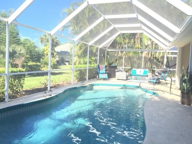A screened-in swimming pool with patio furniture sits under a white frame enclosure — 3001 KING TARPON DRIVE, PUNTA GORDA, FL