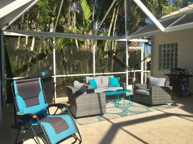 A screened-in patio features outdoor wicker furniture, a blue lounge chair, and a grill — 3001 KING TARPON DRIVE, PUNTA GORDA, FL