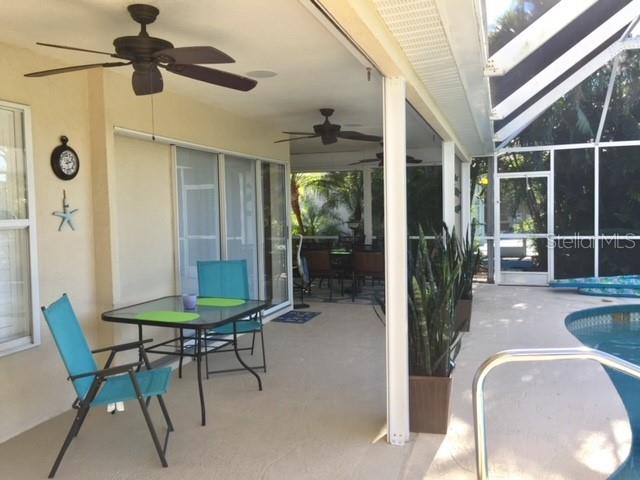 A covered patio features a dining set, ceiling fans, and a view of a swimming pool — 3001 KING TARPON DRIVE, PUNTA GORDA, FL