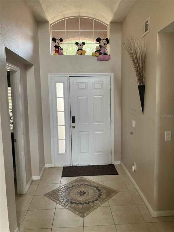 A tiled entryway features a white front door, a decorative floor inlay, and arched window — 345 SOLANA CIRCLE, DAVENPORT, FL