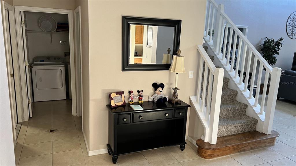 A foyer features a black console table, a mirror, and a staircase with carpeted steps — 345 SOLANA CIRCLE, DAVENPORT, FL