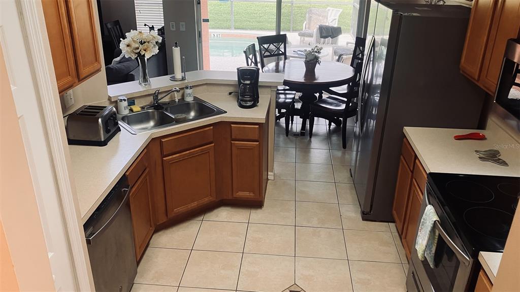A kitchen with wood cabinets, stainless steel appliances, and a dining area overlooking a pool — 345 SOLANA CIRCLE, DAVENPORT, FL