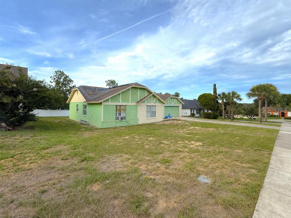 A lime green single-story house with a brick facade and a large front yard — 7755 BAY CEDAR DRIVE, ORLANDO, FL