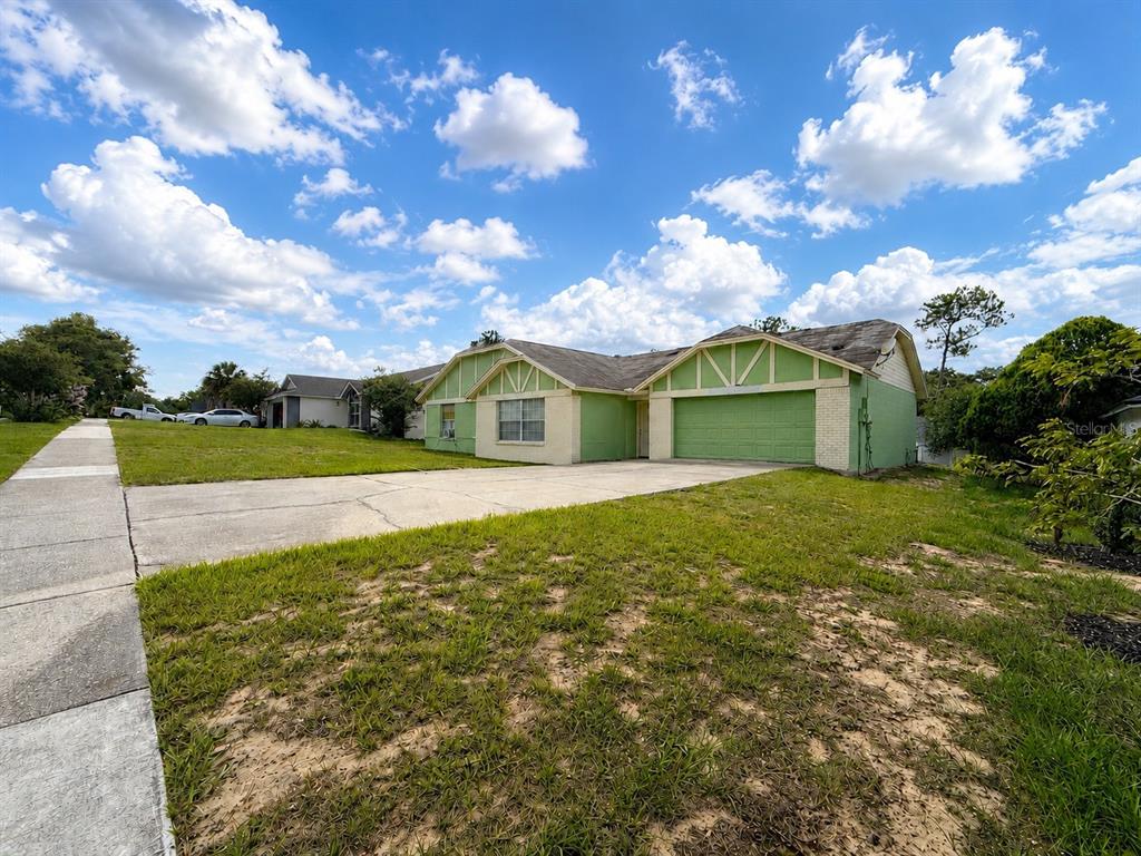 A single-story house with a green exterior, a two-car garage, and a concrete driveway — 7755 BAY CEDAR DRIVE, ORLANDO, FL