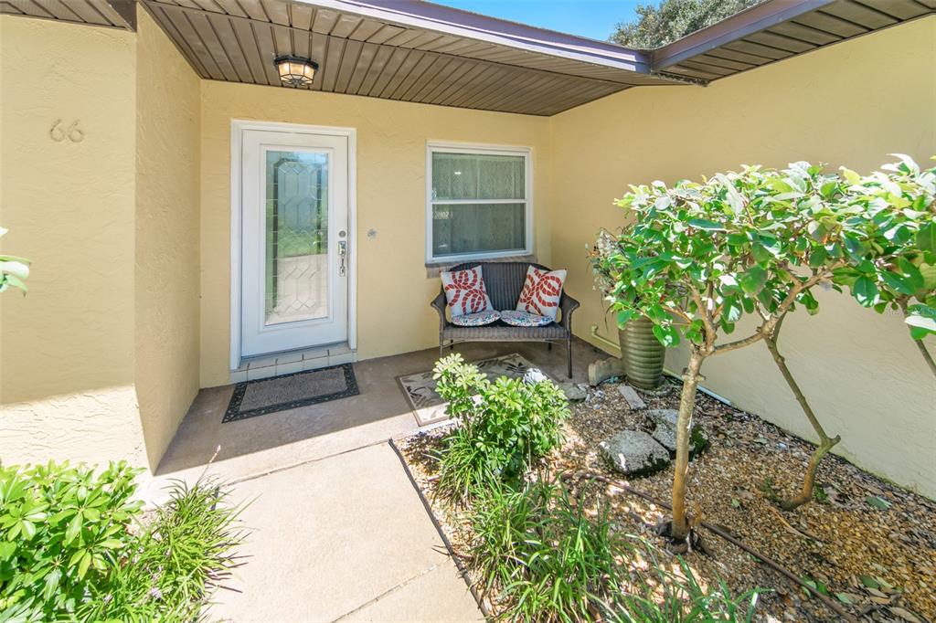 A front entryway features a white door, a small bench, and a landscaped garden bed — 66 BEVERLY HILLS AVENUE, PONCE INLET, FL