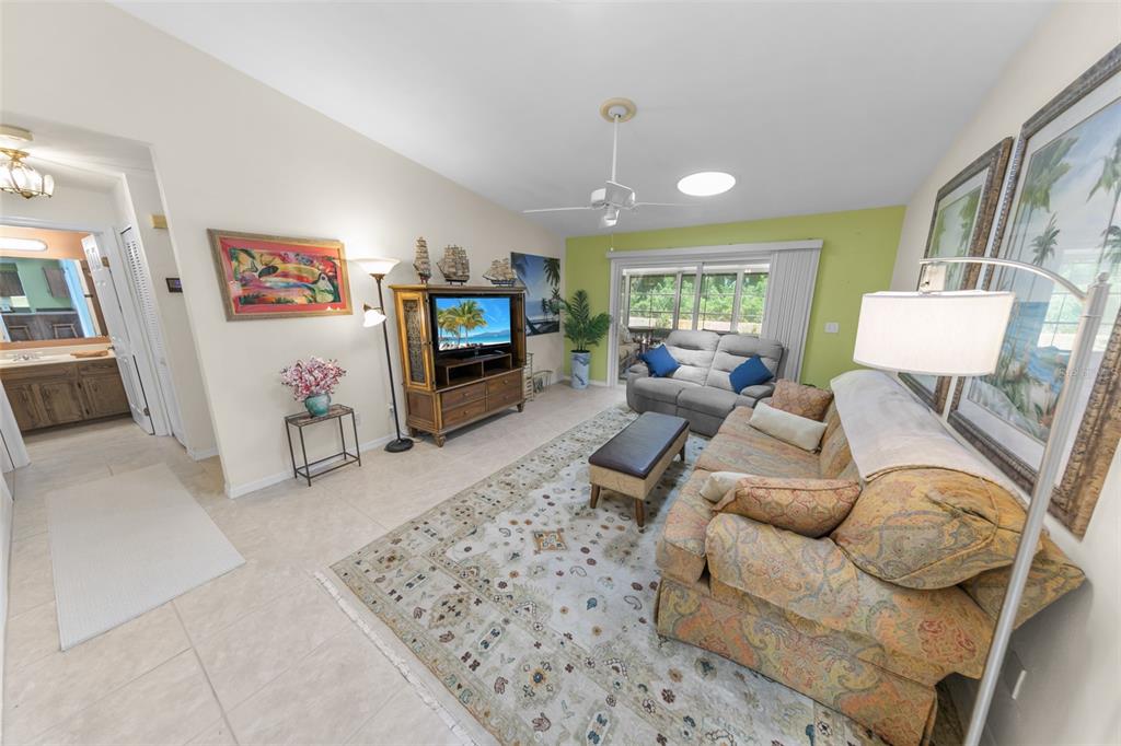 A living room features a patterned sofa, a television console, and a light green accent wall — 66 BEVERLY HILLS AVENUE, PONCE INLET, FL