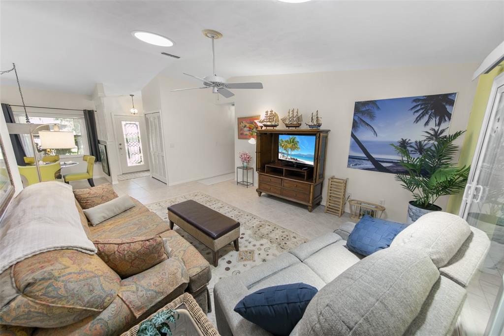 A living room features a patterned sofa, a grey loveseat, and a wooden media console — 66 BEVERLY HILLS AVENUE, PONCE INLET, FL