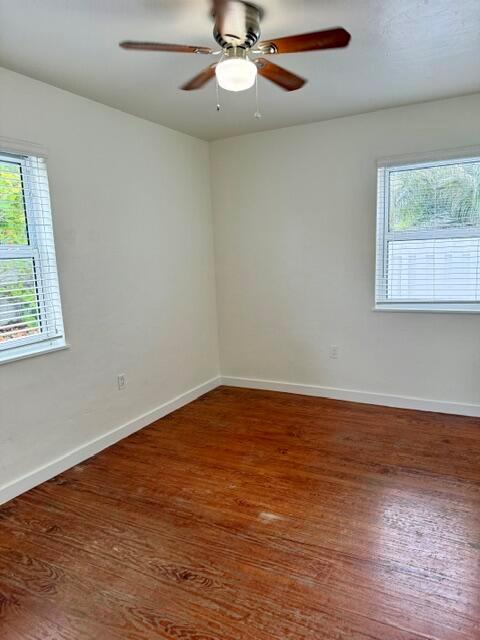 An empty room features hardwood floors, a ceiling fan, and a window overlooking trees — 715 2nd Avenue S # 3, FL 33460, FL