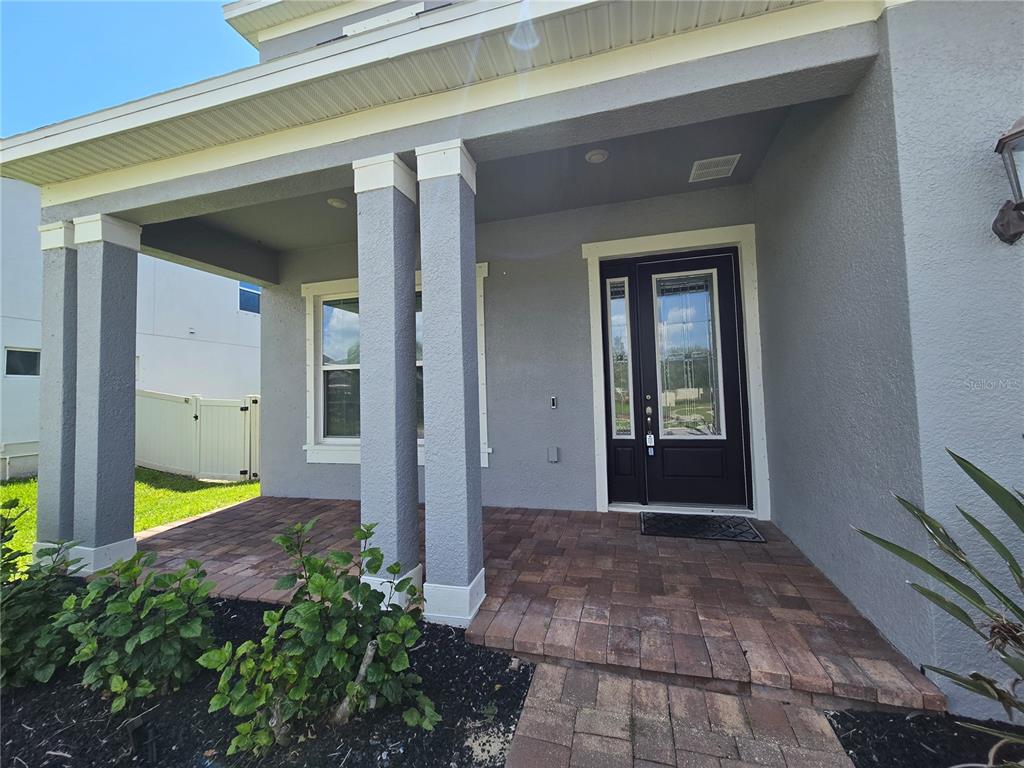 A gray house exterior features a covered porch with stone pavers and a dark front door — 863 W BAYSHORE DRIVE, TARPON SPRINGS, FL