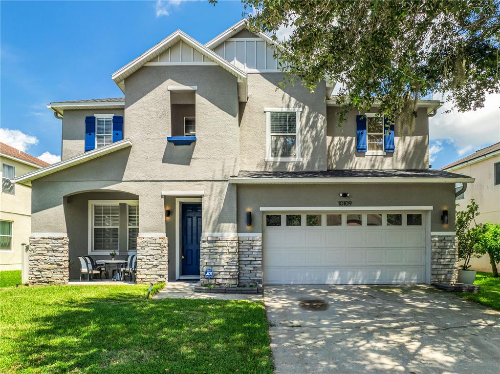 A two-story suburban house with a stone-accented facade, a blue front door, and a garage — 10109 STRATFORD POINTE AVENUE, ORLANDO, FL