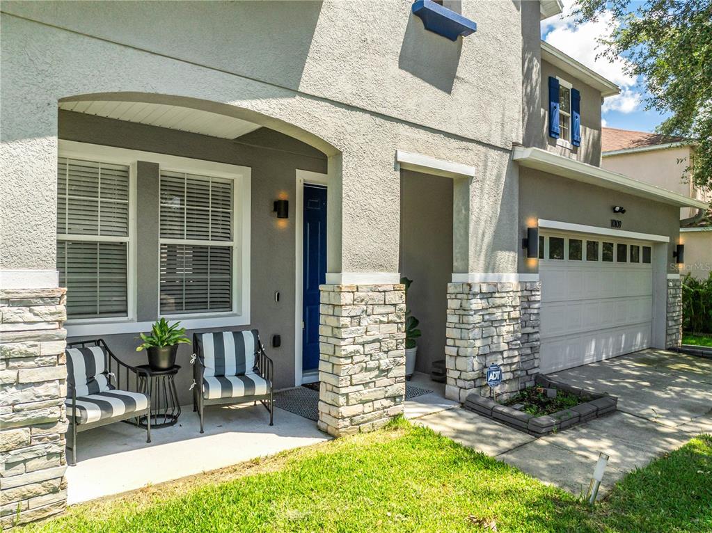 A two-story house exterior features a stone-accented porch, a blue front door, and a garage — 10109 STRATFORD POINTE AVENUE, ORLANDO, FL