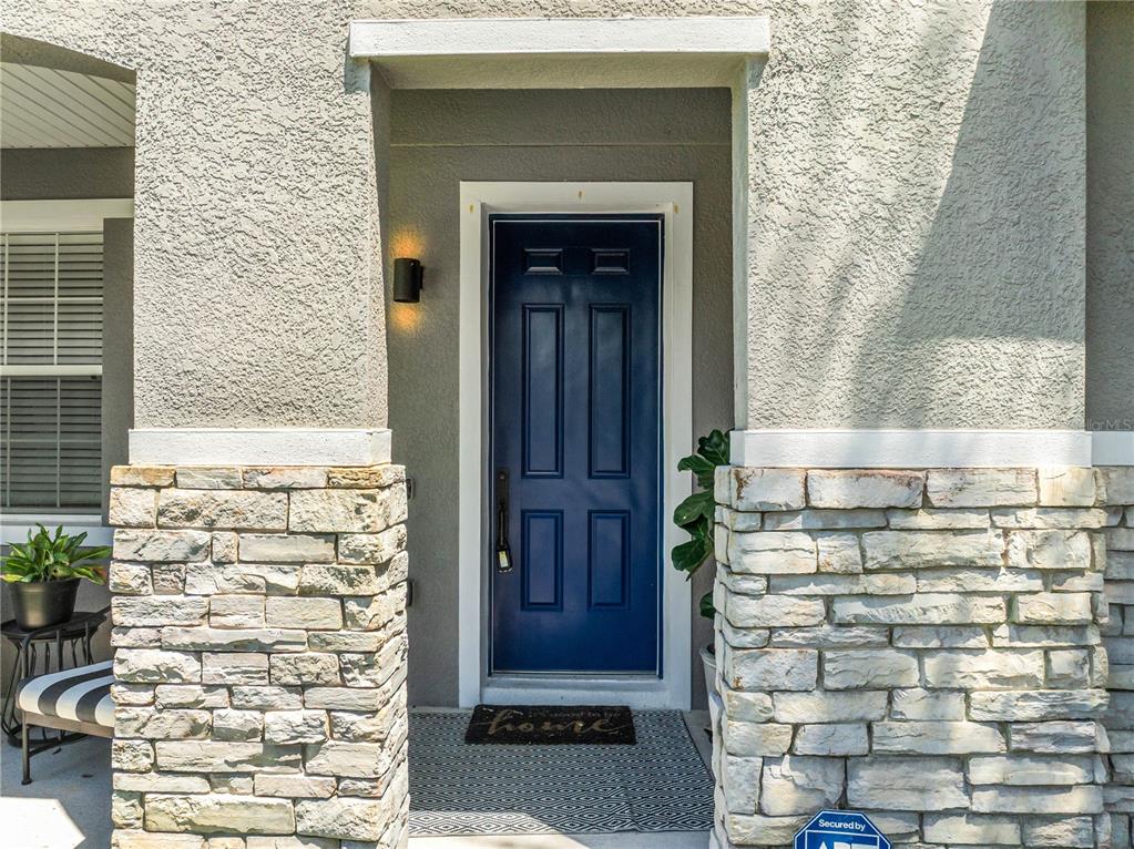A blue front door is set within a recessed entryway featuring stone veneer siding — 10109 STRATFORD POINTE AVENUE, ORLANDO, FL