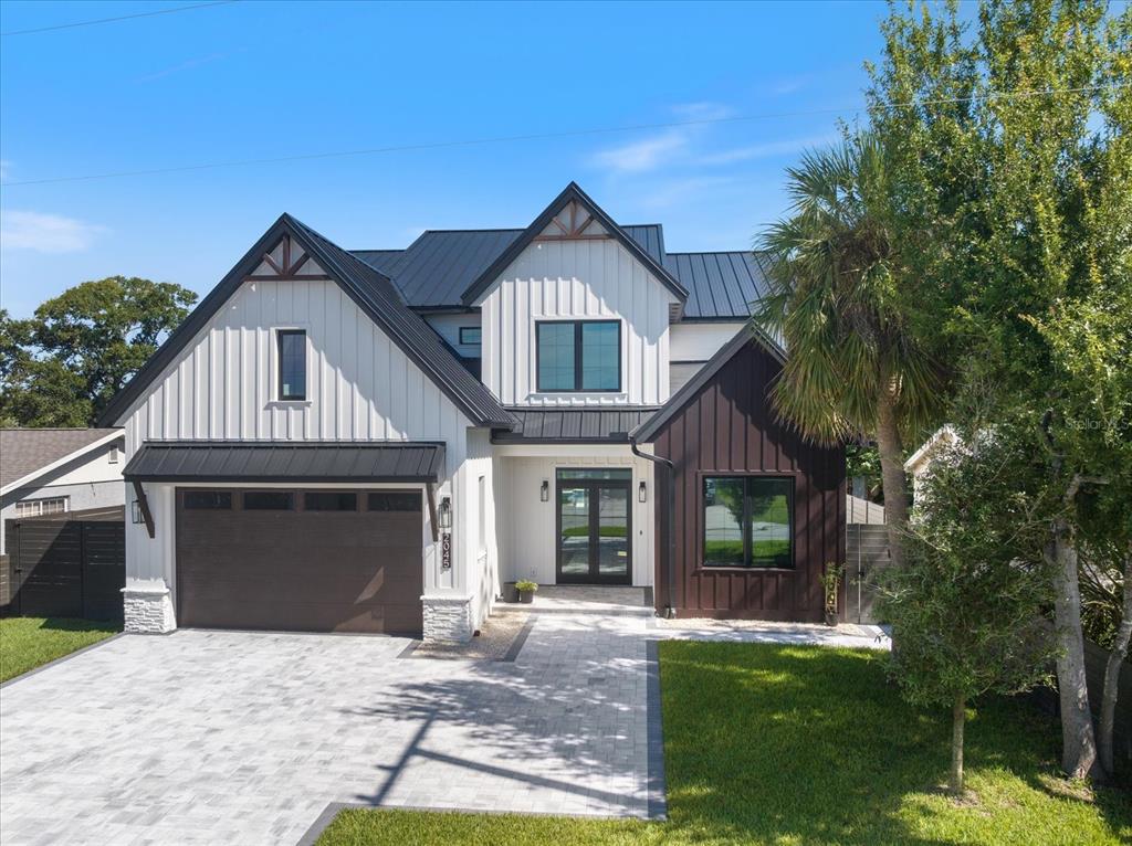 A two-story modern farmhouse with white vertical siding, a dark metal roof, and a driveway — 2045 GOLDENROD STREET, SARASOTA, FL