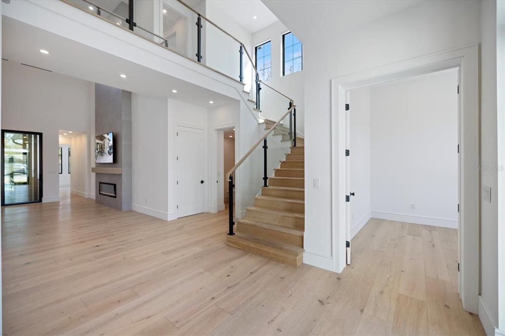 A bright, modern foyer features light wood floors, a glass-railed staircase, and white walls — 2045 GOLDENROD STREET, SARASOTA, FL