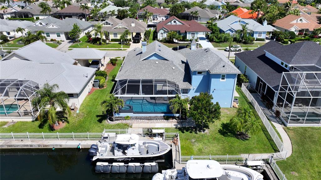 An aerial view of a blue waterfront house with a pool and a boat dock — 4748 COMPASS DRIVE, BRADENTON, FL