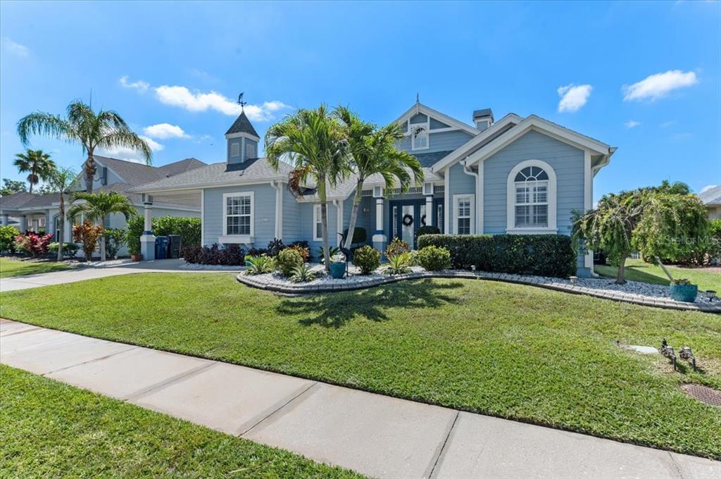A light blue single-story house with a cupola, palm trees, and a landscaped front yard — 4748 COMPASS DRIVE, BRADENTON, FL