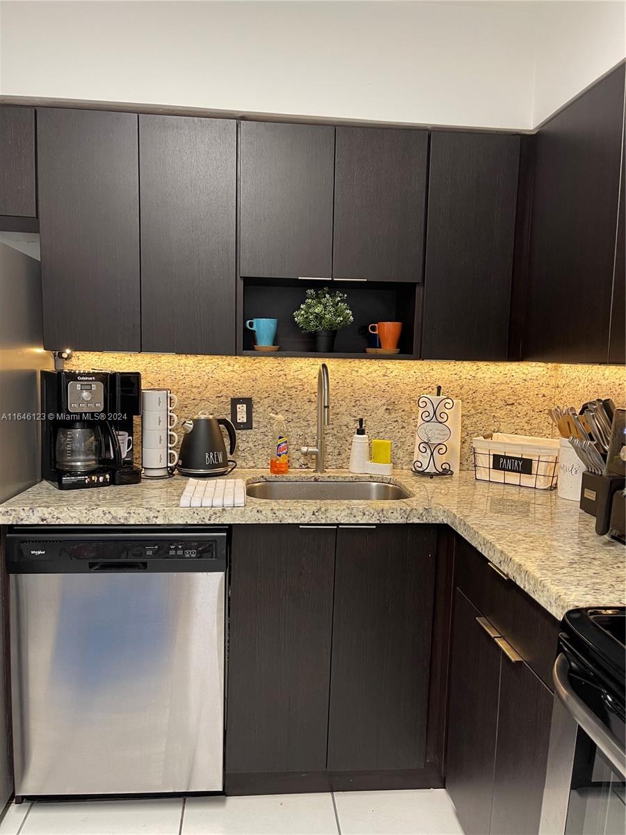 A kitchen features dark wood cabinets, granite countertops, a stainless steel dishwasher, and under-cabinet lighting — 5151 Collins Ave # 629, Miami Beach FL 33140, MIAMI BEACH, FL