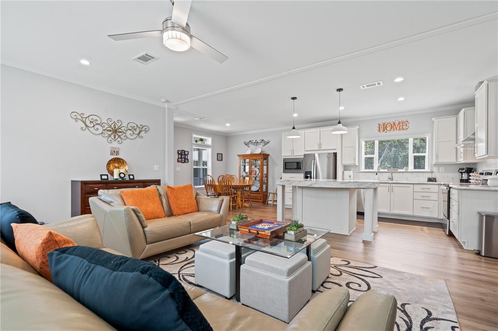 An open-concept living room and kitchen featuring light wood floors, white cabinetry, and neutral furniture — 7039 S STRAIGHT AVENUE, HOMOSASSA, FL