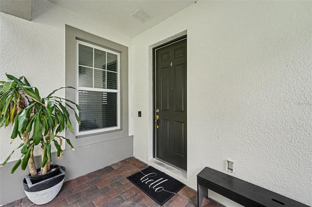 A front entryway features a dark door, a window, a potted plant, and a bench — 15680 ORANGE HARVEST LOOP, WINTER GARDEN, FL