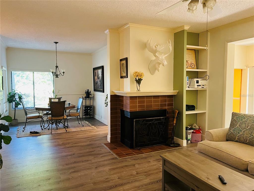 A living room with a brick fireplace, a moose head mount, and an adjacent dining area — 1721 LAKE CYPRESS DRIVE UNIT 2101, SAFETY HARBOR, FL